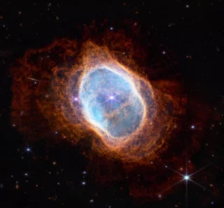 Colorful image of the Southern Ring Nebula, showing a glowing cloud of gas and dust around a dying star.
